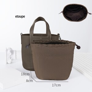 May include: A brown leather tote bag with a top handle and a drawstring dust bag. The bag measures 18 cm tall, 8 cm wide, and 17 cm long. The bag is labelled "etoupe".