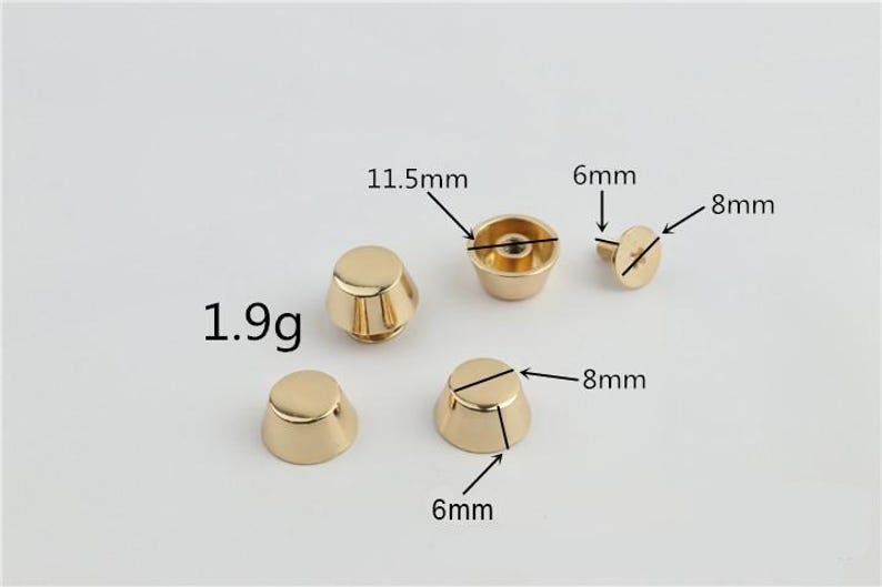May include: Gold-coloured metal studs with measurements labelled. The studs are cone-shaped, with some having a flat top and others a rounded top. The weight is 1.9g. Dimensions are 6mm, 8mm, and 11.5mm.