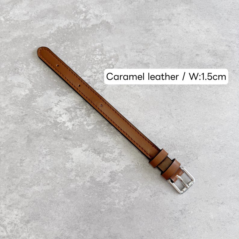 May include: A caramel leather watch strap featuring a silver-toned metal buckle and two matching leather keepers. The strap has a smooth finish with visible stitching along the edges and includes the text Caramel leather / W:1.5cm.