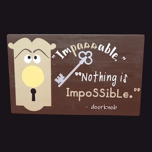 May include: A brown wooden sign with a cartoon door knob and the text "'Impossible.' "Nothing is ImpoSSible." - doorknob"
