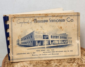 May include: A vintage black and white photo of a building with the text "Mississippi Stationery Company, Printers and Office Outfitters" above the building. The text "Organized Jan. 3, 1927. New Home Jan. 1940. Acquired Own Building Jan. 30, 1939. Growing with Jackson and Mississippi." is below the building.