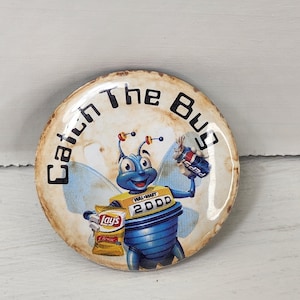 May include: A round, vintage-style button with the text "Catch The Bug." The button features a cartoon blue bug holding a bag of Lay's chips and a Pepsi can. The bug has a yellow Walmart 2000 uniform.