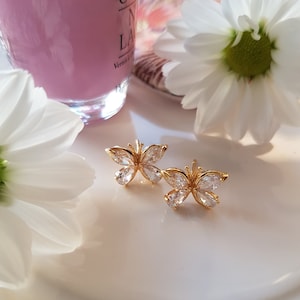May include: A pair of gold butterfly earrings with clear cubic zirconia stones.