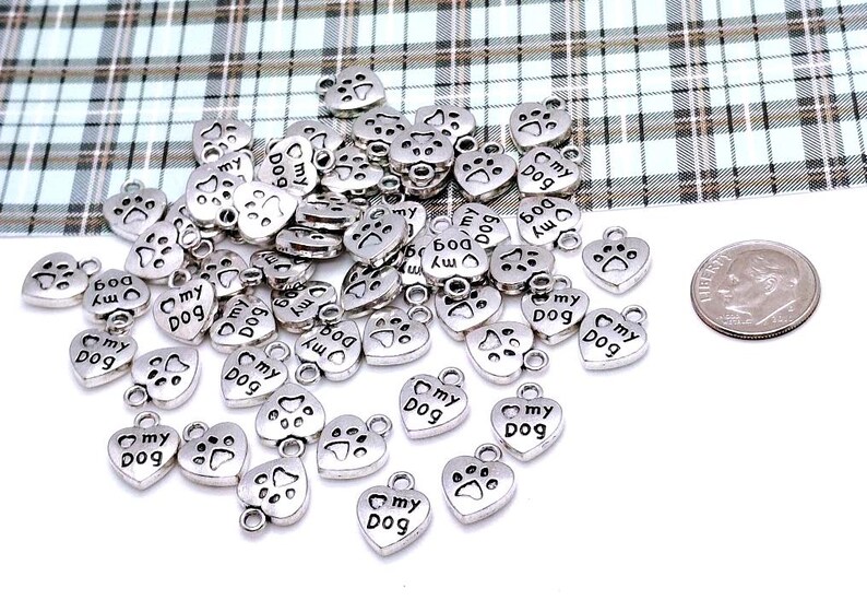 May include: A large quantity of silver-toned metal charms in the shape of a heart with the words "My Dog" and a paw print.