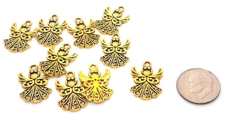 May include: Ten gold angel charms with intricate details. The charms are about the size of a US dime.