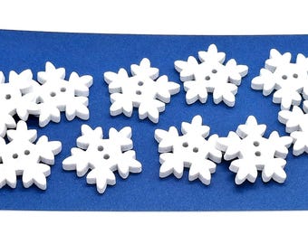 Puede incluir: Diez botones de madera blancos en forma de copo de nieve con un diseño de estrella de seis puntas. Los botones están dispuestos en semicírculo sobre un fondo azul.