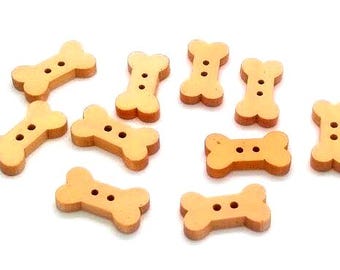 May include: A collection of light brown wooden buttons shaped like dog bones. Each button has two holes for sewing. The buttons are scattered on a white surface, ideal for craft projects or pet-themed creations.