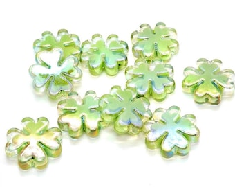 May include: A collection of ten four-leaf clover shaped beads with a translucent light green color and an iridescent finish. Each bead features a central hole for threading, with smooth, rounded edges and a glossy, reflective surface texture.