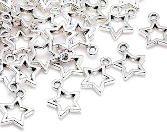 May include: A collection of silver-colored metal star charms, each featuring a hollow center and a small circular loop at the top for attachment. The charms are scattered across the frame, displaying a consistent five-pointed star shape.