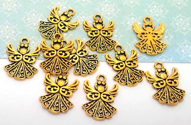 May include: Ten gold-colored angel charms with intricate details. Each charm features a stylized angel with wings and a halo. The charms are perfect for adding a touch of elegance to jewelry, crafts, or home decor.