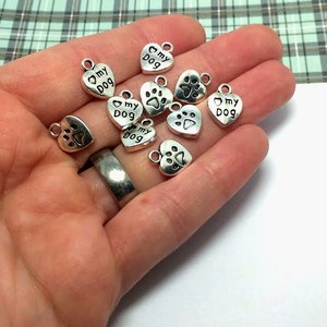 May include: A collection of silver-toned metal charms in the shape of hearts. Some charms feature the text "My Dog" and a paw print.