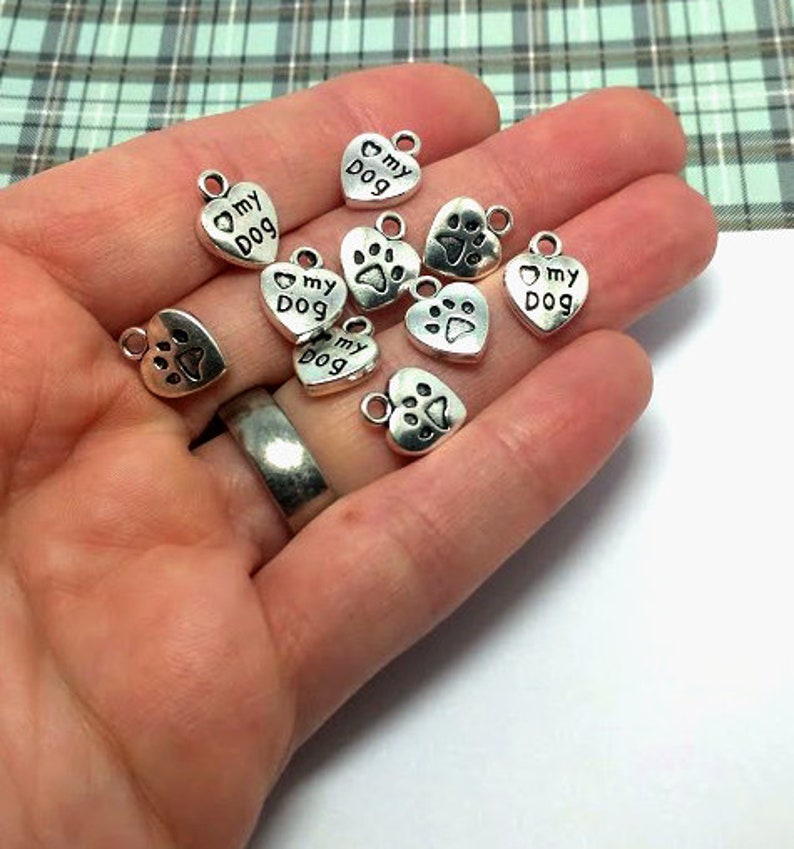 May include: A collection of silver-toned metal charms in the shape of hearts. Some charms feature the text "My Dog" and a paw print.