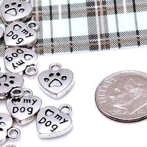 May include: Silver heart-shaped charms with the words "My Dog" and a paw print design. The charms are about the size of a US dime.
