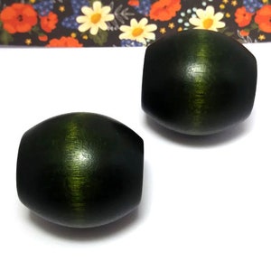 May include: Two dark green wooden oval beads with a lighter green stripe down the center.