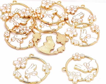 May include: Gold-toned metal charms featuring white rabbits with bows and floral accents. The charms are circular, with a bunny in the center surrounded by flowers. These charms are ideal for jewelry making or crafting projects.