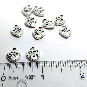 May include: Silver heart-shaped charms with the words "I love my dog" and a paw print design. The charms are approximately 1 inch in size.