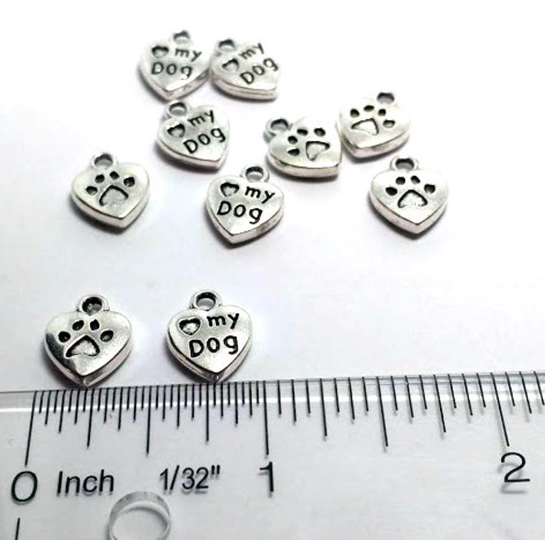 May include: Silver heart-shaped charms with the words "I love my dog" and a paw print design. The charms are approximately 1 inch in size.