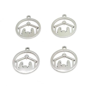 May include: Four silver-colored Christmas ornaments. Each ornament features a circular frame with a nativity scene silhouette inside. The scene includes figures under a roof with a star above. Each ornament has a small loop at the top for hanging.