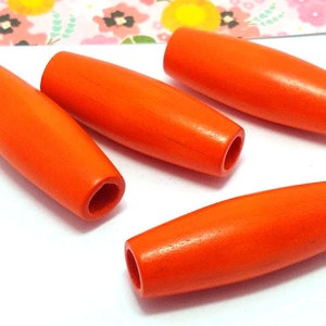 May include: Four orange wooden beads with a hole through the center. The beads are oval shaped and have a smooth, polished finish.