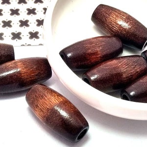 May include: A group of eight brown wooden beads with a smooth, polished finish. The beads are oval-shaped and have a natural wood grain pattern.