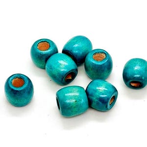 May include: A collection of eight turquoise wooden beads. Each bead is cylindrical with a hole running through the center, revealing a natural wood color. The beads are scattered against a white background.