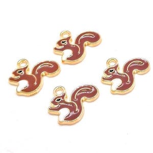 May include: Four squirrel-shaped charms featuring a gold-tone metal outline and a dark reddish-brown enamel fill with white accents on the chest and tail. Each charm includes a small circular loop at the top for attachment to jewelry or crafts.