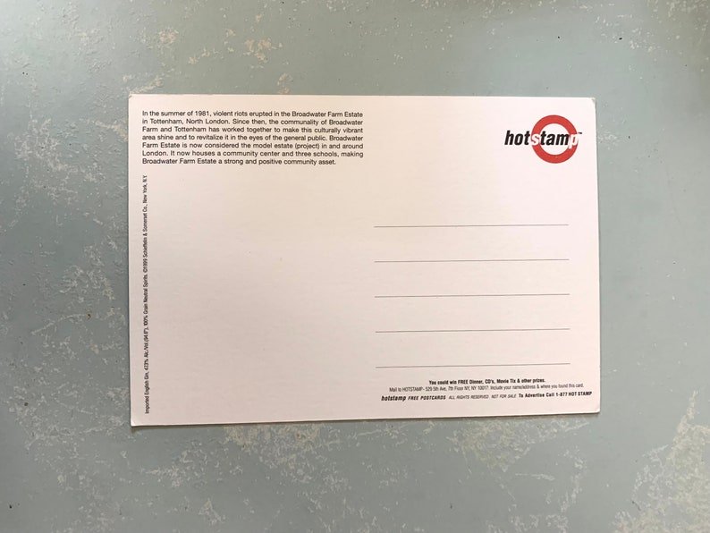 Pode incluir: Um cart&atilde;o postal branco com texto sobre Broadwater Farm Estate em Tottenham, North London, e um logotipo "hotstamp" vermelho e branco. O cart&atilde;o postal est&aacute; sobre uma superf&iacute;cie texturizada azul clara.