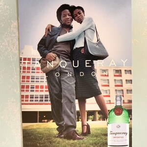 Pode incluir: Um an&uacute;ncio de Tanqueray London Dry Gin. A imagem apresenta um casal abra&ccedil;ado, com uma garrafa de gin em primeiro plano. O texto diz "Tanqueray London" e "London Dry Gin, Distinctively Crisp, Since 1830."