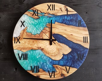 Può includere: Un quadrante di orologio rotondo in legno con numeri romani e accenti in resina epossidica blu e verde. Il quadrante dell'orologio è in legno con una venatura naturale.