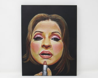 May include: An oil painting on canvas depicts a woman applying lipstick. The woman has brown hair, pink eyeshadow, and a nose ring. The background is black. The lipstick is silver and the woman's skin is fair.