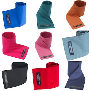 Può includere: Una collezione di nove cinghie in tessuto di vari colori, tra cui blu, verde acqua, arancione, rosa, rosso e nero. Ogni cinghia è arrotolata e presenta un'etichetta rettangolare con il testo "THE ROPESTRY".