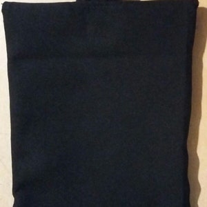 May include: A solid black fabric bag with a rectangular body and a rectangular handle attached at the top. The bag is made of a soft, matte material. The handle is folded over.