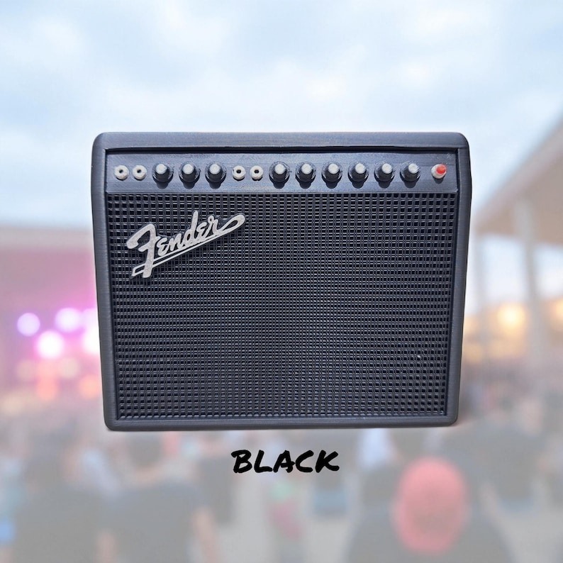 May include: Black Fender guitar amplifier with a speaker grill and control knobs. The Fender logo is visible on the front. The word "BLACK" is written in a bold font below the amplifier.