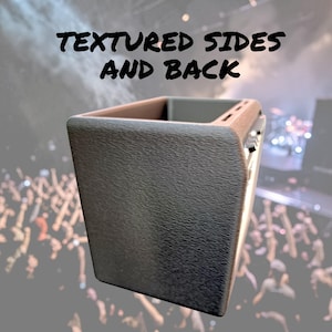 May include: A dark gray, rectangular object with textured sides and back. The top edge is a lighter brown color. The text "TEXTURED SIDES AND BACK" is displayed in black at the top of the image. The background is a blurred image of a crowd.