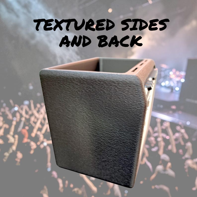 May include: A dark gray, rectangular object with textured sides and back. The top edge is a lighter brown color. The text "TEXTURED SIDES AND BACK" is displayed in black at the top of the image. The background is a blurred image of a crowd.