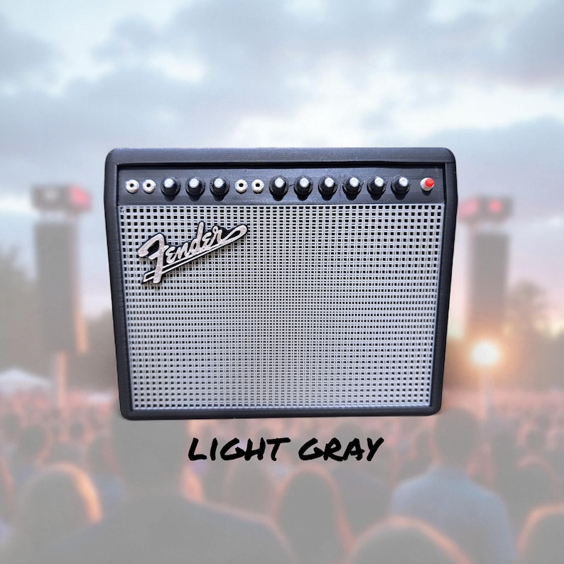 May include: A black and light gray Fender amplifier with a silver speaker grill. The amplifier has several knobs and a red light. The word "Fender" is written in cursive on the front. The text "LIGHT GRAY" is written below the amplifier.