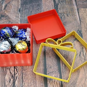 Christmas gift card holder shown filled with Lindor chocolates. Lid and ribbons are shown nearby.