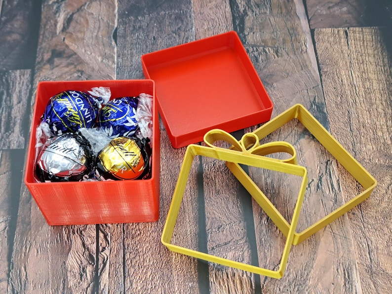 Christmas gift card holder shown filled with Lindor chocolates. Lid and ribbons are shown nearby.
