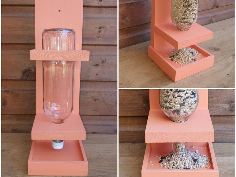 May include: A pink wooden bird feeder with two platforms. The top platform has a clear glass bottle for holding birdseed. The bottom platform has a tray for catching spilled seed.