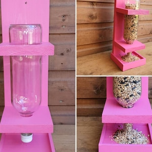 May include: Pink wooden bird feeder with a clear plastic bottle for holding birdseed. The feeder has three shelves and a small tray at the bottom.