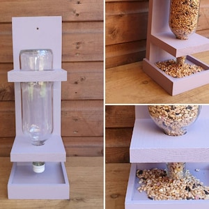 May include: Purple wooden bird feeder with two platforms. The top platform has a clear glass bottle for holding birdseed. The bottom platform has a tray for catching spilled seed.