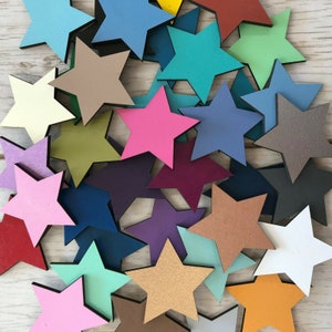 Peut inclure: Un assortiment d'étoiles en bois de différentes couleurs, dont le rose, le bleu, le vert et le marron. Les étoiles sont disposées sur une surface en bois de couleur claire, créant un agencement visuellement attrayant. Ces étoiles décoratives sont idéales pour les travaux manuels et les projets de bricolage.