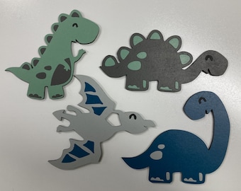 May include: Four cutout dinosaur shapes in various colors. A green dinosaur, a gray dinosaur with a green spine, a gray dinosaur with blue wings, and a blue dinosaur.