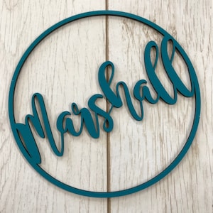 Peut inclure: Un cercle en bois bleu turquoise avec le nom "Marshall" écrit en cursive.