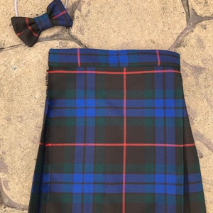 May include: A black, blue, and red plaid kilt with a white headband and a blue bow tie.