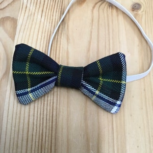 May include: A tartan bow tie in green, navy, yellow, and white, with an elastic strap. The bow tie has a traditional plaid design, suitable for formal or casual occasions.