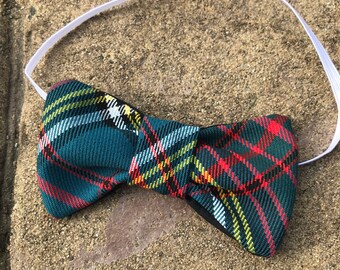 Könnte beinhalten: Eine karierte Fliege mit teal-farbenem Hintergrund und roten, gelben und weißen Akzenten. Die Fliege ist an einem weißen Gummiband befestigt, ca. 12 cm breit.