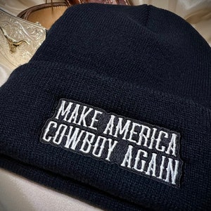 May include: Black beanie with a white embroidered patch that reads "Make America Cowboy Again".