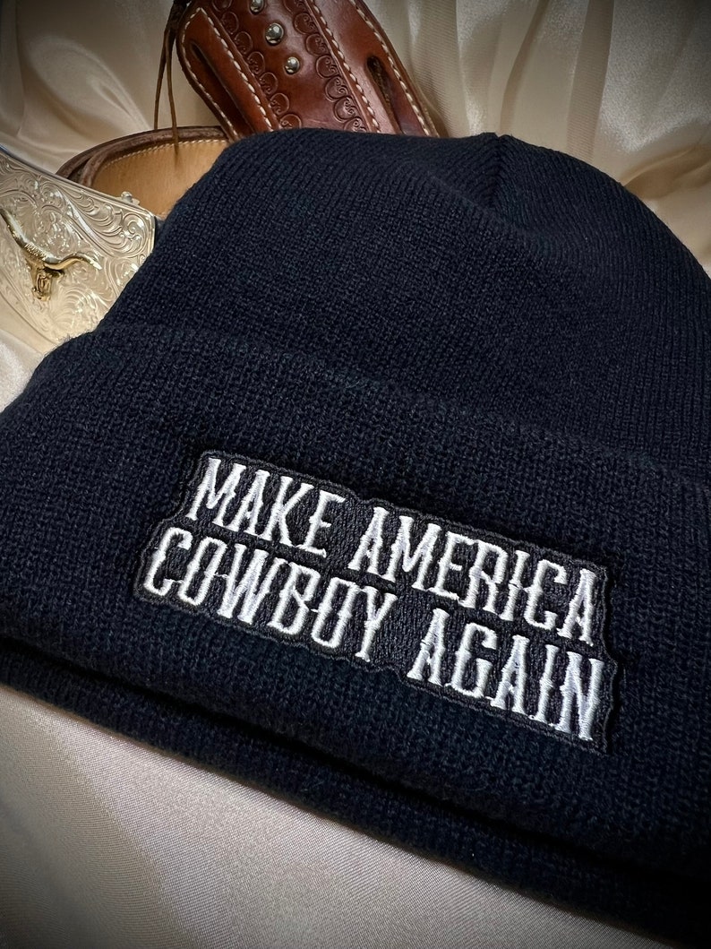 May include: Black beanie with a white embroidered patch that reads "Make America Cowboy Again".
