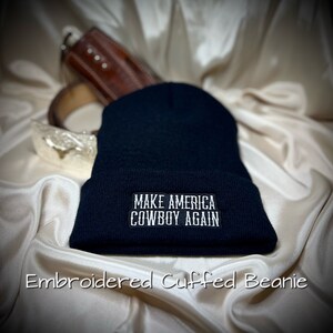 May include: Black embroidered beanie with the text "Make America Cowboy Again" in white.